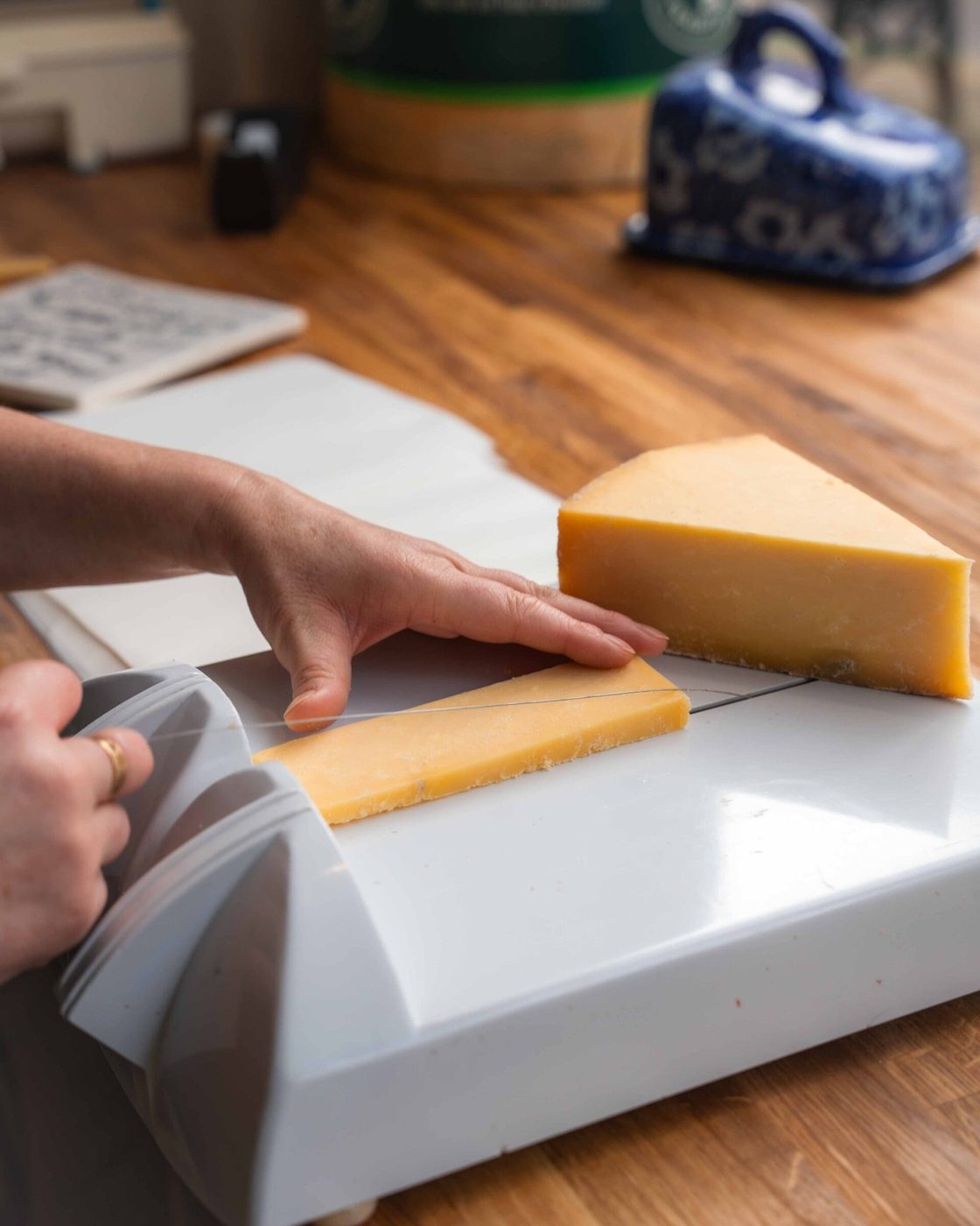 A wedge of cheddar cut to order on the cheese wire at Truffles, with a blue and white butter dish on the oak counter