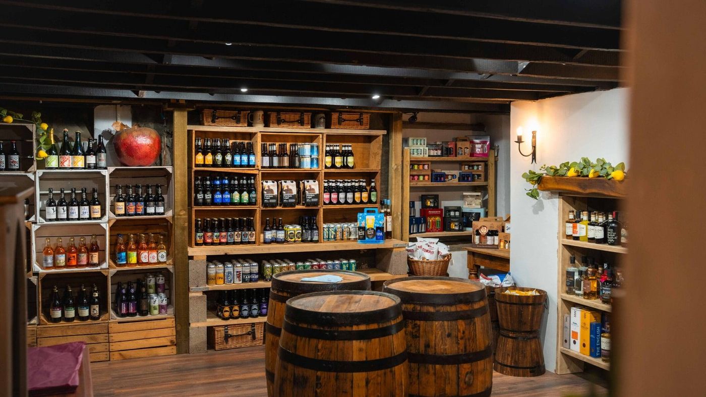 The cider and beer cellar at Truffles, with oak crate shelving and whisky-barrel tables under black ceiling beams